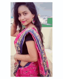a woman wearing a pink and blue saree and earrings