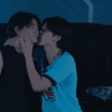 a man in a blue shirt is kissing another man on the cheek