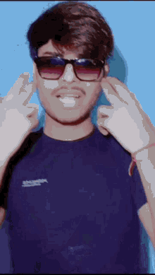 a man wearing sunglasses and a blue shirt is making a funny face .