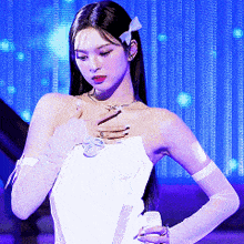 a woman wearing a white dress and gloves is standing in front of a blue curtain