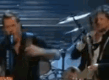 a blurry picture of a group of men playing instruments on a stage .