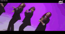 a group of women are dancing in front of a purple wall .