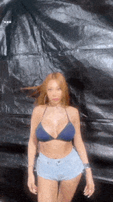 a woman in a bikini top and denim shorts is posing for a picture .