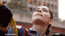 a woman is climbing a rope with the nbc logo in the background