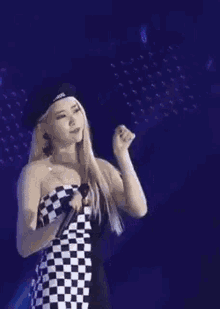 two women are hugging each other on a stage . one of the women is wearing a black and white checkered top .