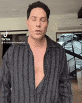 a man wearing a black striped shirt has a tiktok account behind him