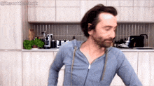 a man in a blue sweatshirt is dancing in a kitchen with the hashtag #itsscottiesstark