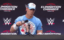 a man wearing a blue shirt that says elimination chamber is holding a microphone