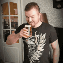a man wearing a t-shirt with a bull on it drinks from a glass