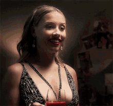 a woman in a very revealing dress is holding a glass of red liquid .
