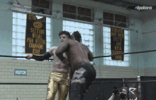 two wrestlers in a ring with a sign that says visitor on it