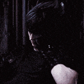 a man with black hair is sitting in a dark room