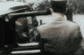 a man in a police uniform is standing in front of a car with the door open .