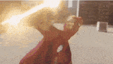 a person in a red superhero costume is holding a lightning bolt .