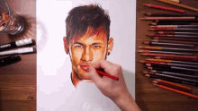 a person is drawing a man 's face with colored pencils on a wooden table