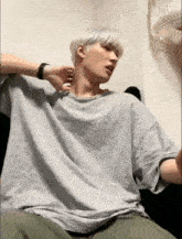 a man with white hair wearing a grey shirt