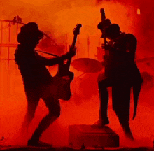 a man in a top hat is playing a guitar in front of a drum set .