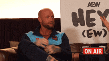 a man is sitting in front of a sign that says hey ( ew )