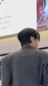 a man in a striped suit is standing in front of a sign that says noodles et eats ragon