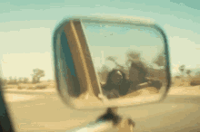 a man and a woman are reflected in a rear view mirror while driving a car .