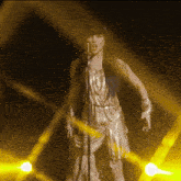 a woman in a gold dress is singing into a microphone on a stage