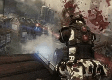 a soldier is kneeling down in a video game while holding a gun in front of a bloody wall .