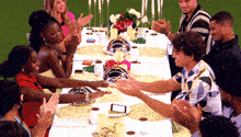a group of people are sitting at a long table with candles on it