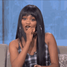 a woman with long black hair is sitting on a couch making a face