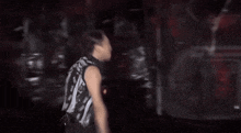 a man is standing in a dark room wearing a black and white tank top .