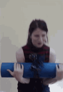 a woman is holding a blue yoga mat in her arms and smiling .