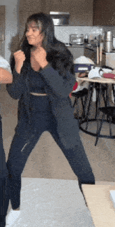 a woman is dancing in a kitchen with a man .