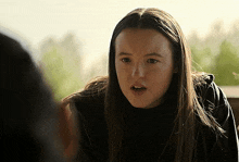 a woman with long hair is looking at the camera with a serious look on her face
