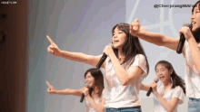 a group of young girls are singing into microphones and pointing at the camera