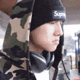 a man wearing headphones and a supreme hat