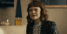 a woman in a leopard print jacket is sitting in front of a sign that says " the boys "