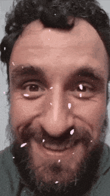 a close up of a man 's face with a beard smiling