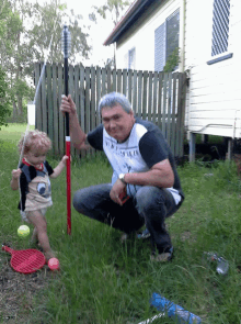 a man wearing a shirt that says new york is kneeling next to a little girl