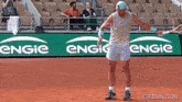 a tennis player stands on a court in front of an engie banner