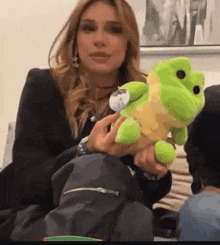 a woman is holding a stuffed green frog in her hands .