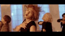 a group of people are dancing in a room and one of them is wearing a black top