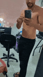 a shirtless man is taking a selfie in front of a mirror