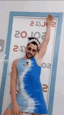 a man in a blue and white dress is standing in front of a door with his arm in the air .