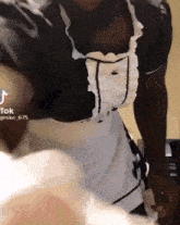 a man in a maid costume is standing in front of a bed .