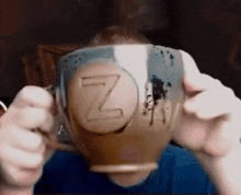 a man is holding a cup with the letter z on it