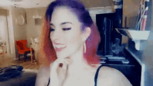 a woman with red hair is standing in a living room and smiling .