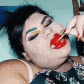 a woman is laying on a bed eating a lollipop .