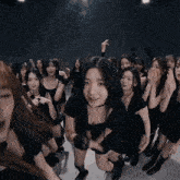 a group of young women in black dresses are dancing in a dark room