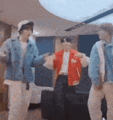 three young men are dancing together in a living room .