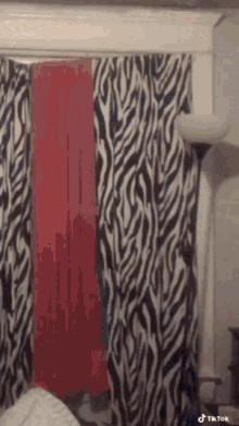 a bedroom with zebra print curtains and a lamp .