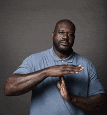 a man wearing a blue shirt is making a stop sign with his hands